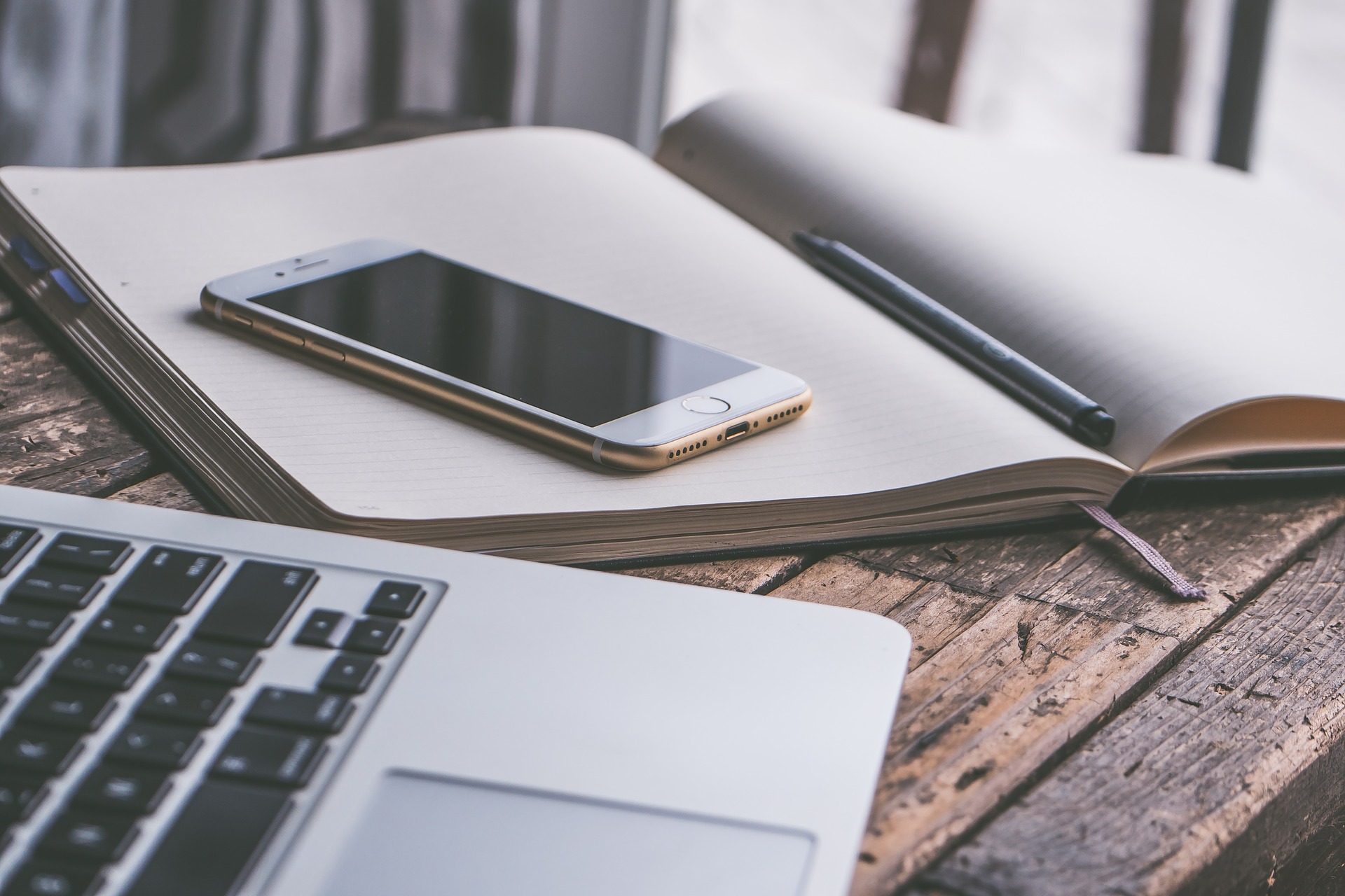 Image depicting an i-phone on a notebook beside a macbook symbolizing benefits of technology