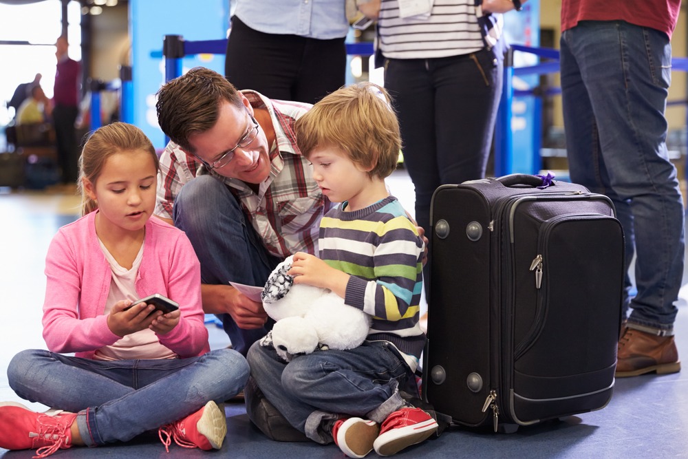 Dad talking to daughter and son getting bored at airport ( activities for teaching patience are lifesaver in such situations) 