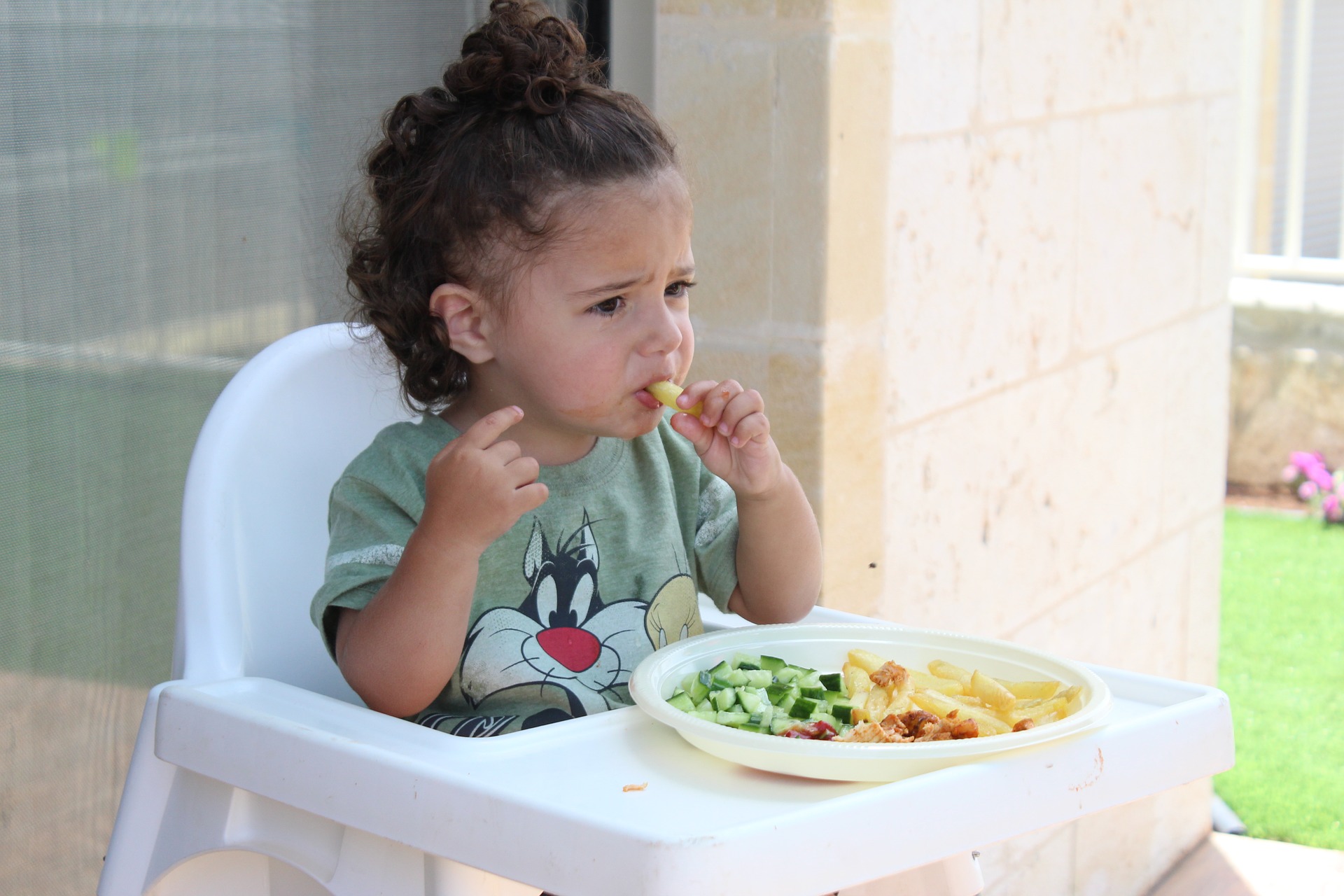 A fussy eater toddler eating his meal in high chair